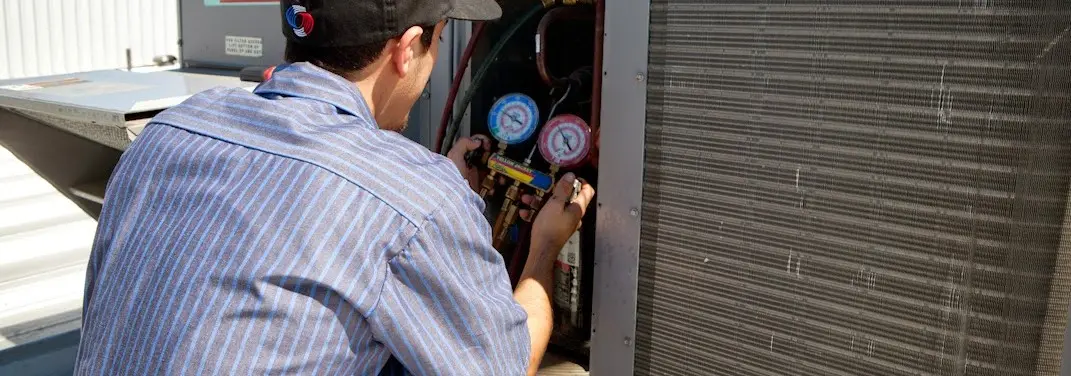 HVAC technician servicing a condenser unit in Destrehan